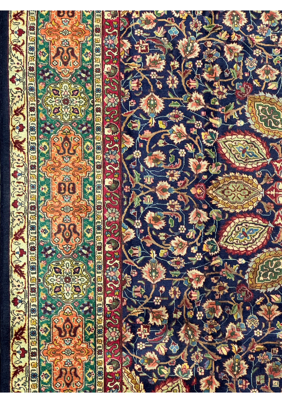 A detailed shot of the corner of the Persian Tabriz Rug, focusing on the border and part of the central field. The intricate floral and geometric patterns in vibrant colors are clearly visible, demonstrating the skill and precision of the craftsmanship. The high knot density contributes to the detailed design and overall durability of the rug.