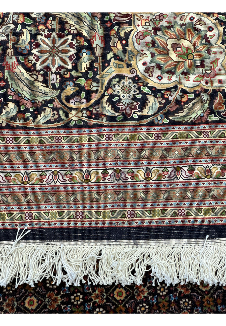 Backside view of a 11'7 x 16'6 Persian Tabriz Mahi 50 Raj rug, focusing on the detailed weave and construction, with fringes and leather binding visible, demonstrating the fine craftsmanship and quality of this luxurious handmade wool and silk rug