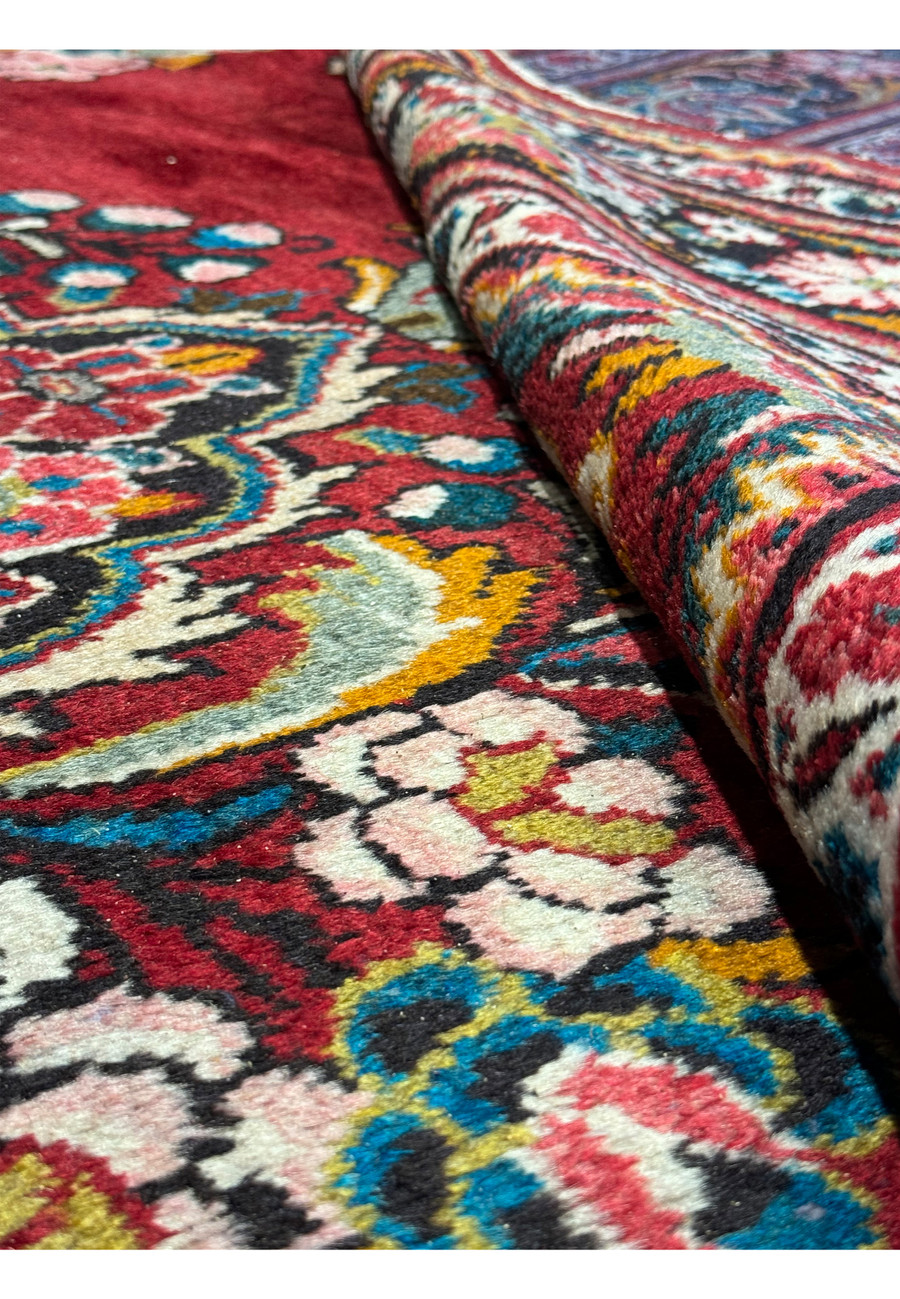View of a 10'7 x 13'5 Persian Mahal rug rolled up to show its wool pile and craftsmanship.