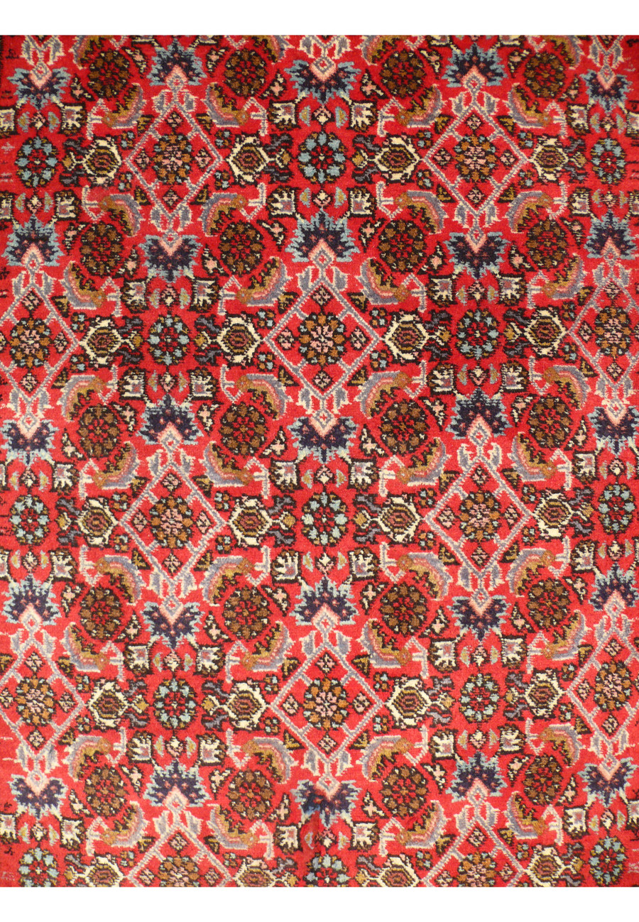 Close-up of the center section of the Persian Bijar runner rug, focusing on the detailed floral motifs and geometric patterns in vibrant red, blue, and ivory. The dense weave and high-quality wool fibers are evident.