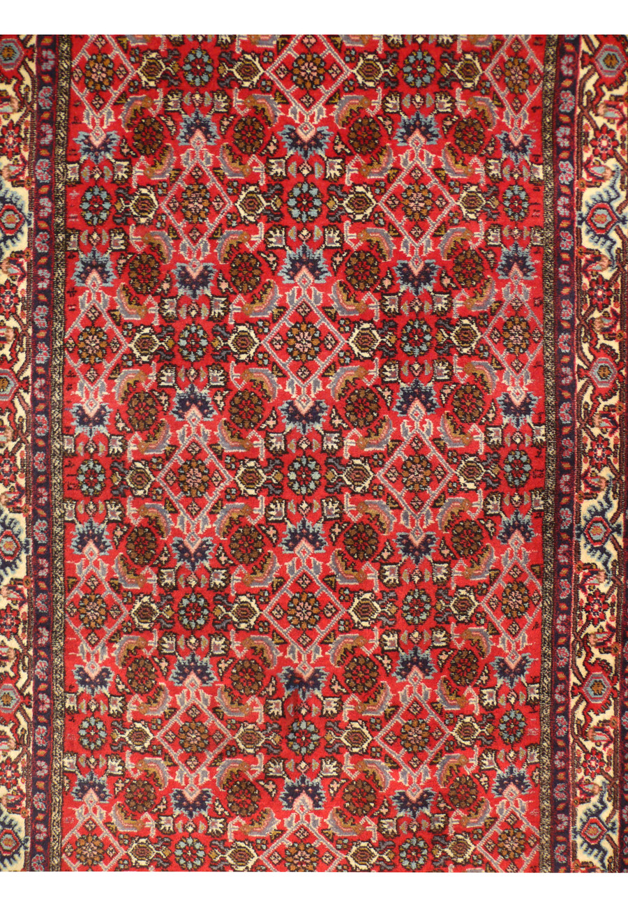 A detailed view of a 3' x 9'9" Persian Bijar runner rug, showcasing its intricate geometric and floral patterns in rich red, blue, ivory, and brown colors. The high-quality wool and tight weave are visible, highlighting the craftsmanship of Bijar weavers.