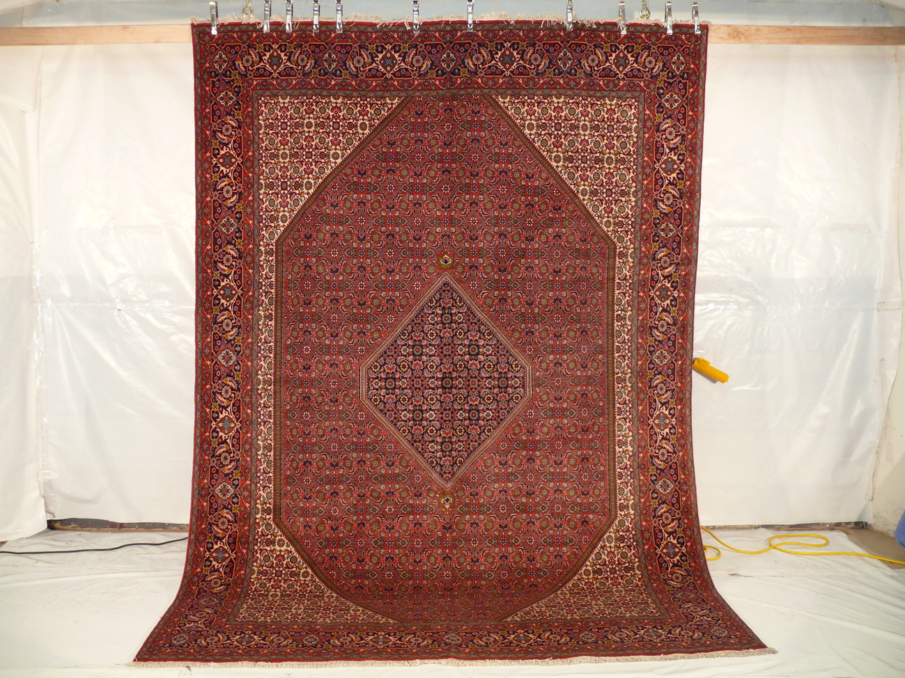 8' x 11'2" Bijar Persian Iron Rug hanging, showcasing intricate floral and geometric patterns.