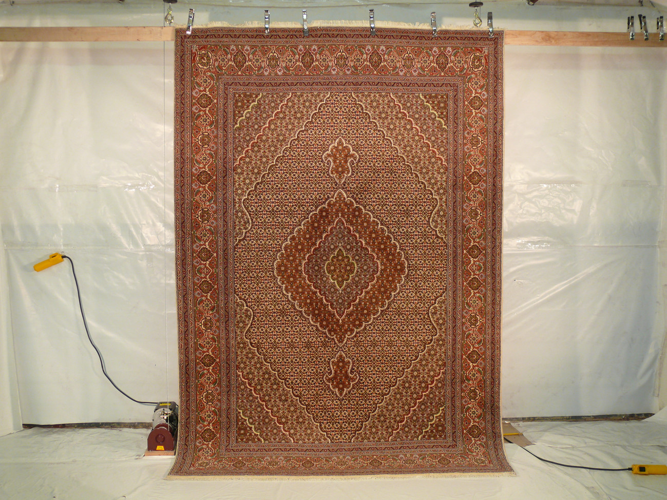 The 6'8" x 9'9" Persian Tabriz Mahi Rug hung for display, revealing its overall pattern and craftsmanship.