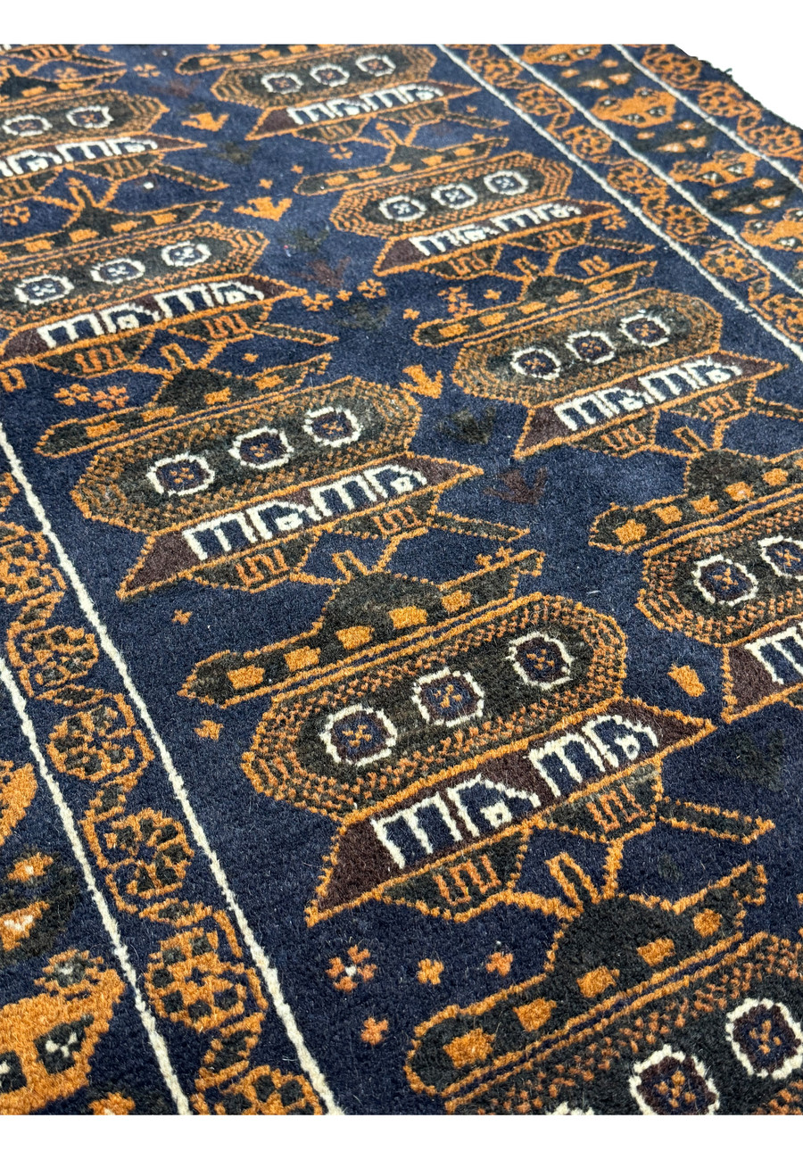 Angled view of the 2'9 x 4'4 Persian Baluch Rug showcasing the depth of the navy and orange tank designs.