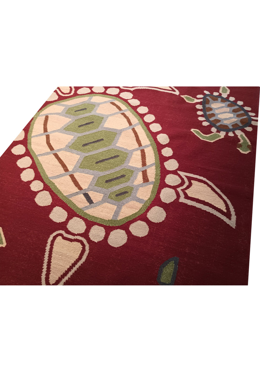 Angled view of burgundy turtle pattern kids rug.