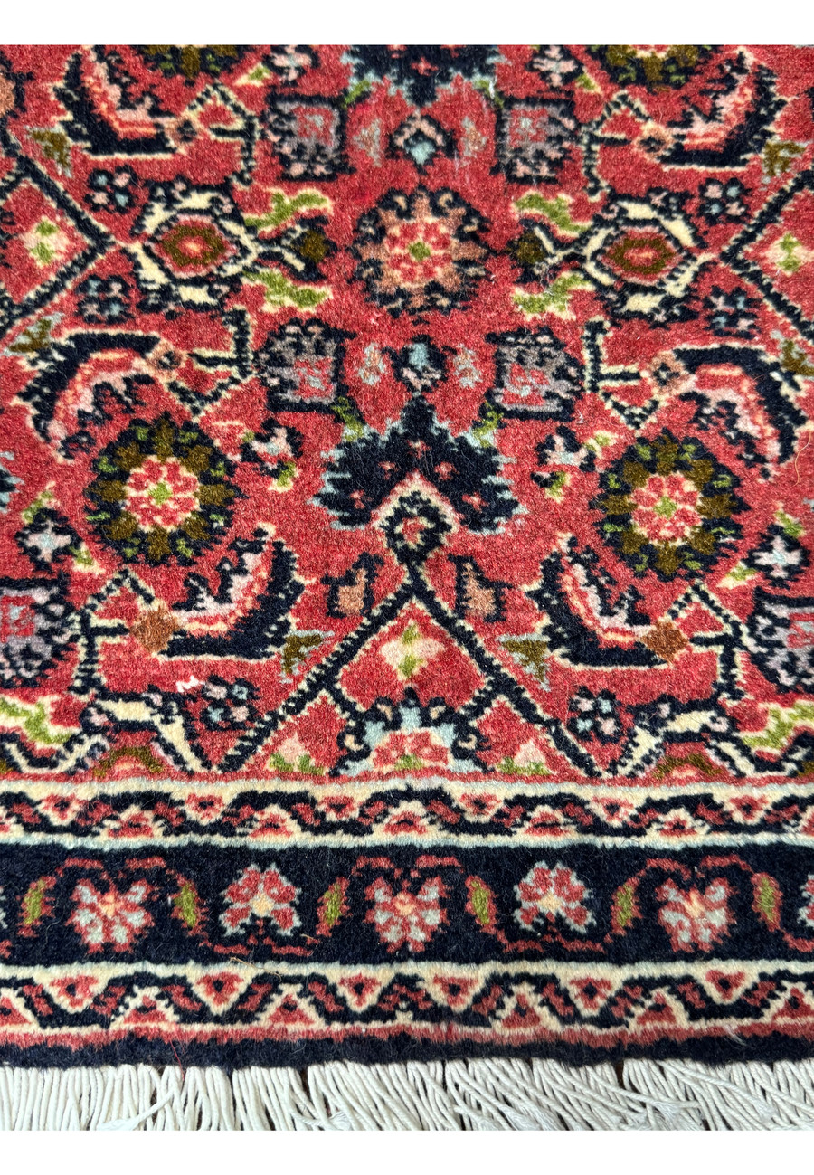 The lower part of a 1'3 x 2' Persian Baby Bijar Rug highlighting floral medallions and a navy border.