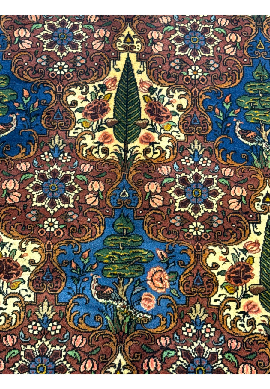 Close-up view of a Persian Bakhtiar rug displaying intricate floral motifs, trees, and birds in a detailed pattern.