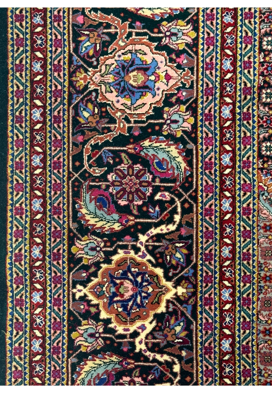 Close-up of the floral border design in the Tabriz rug with repeating vine and flower patterns.