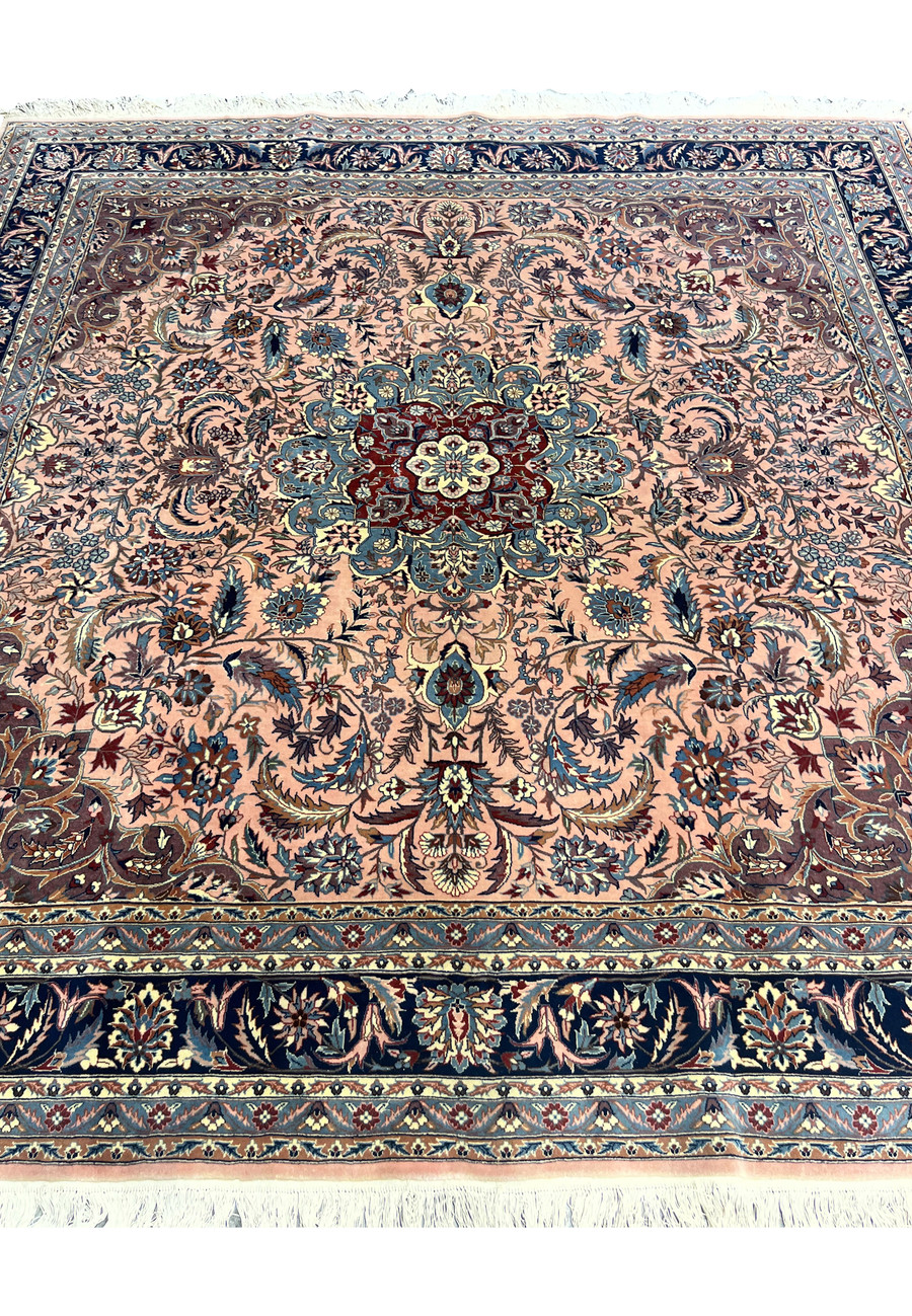 Detailed section of Persian Tabriz rug showing floral field and intricate vine work on salmon background