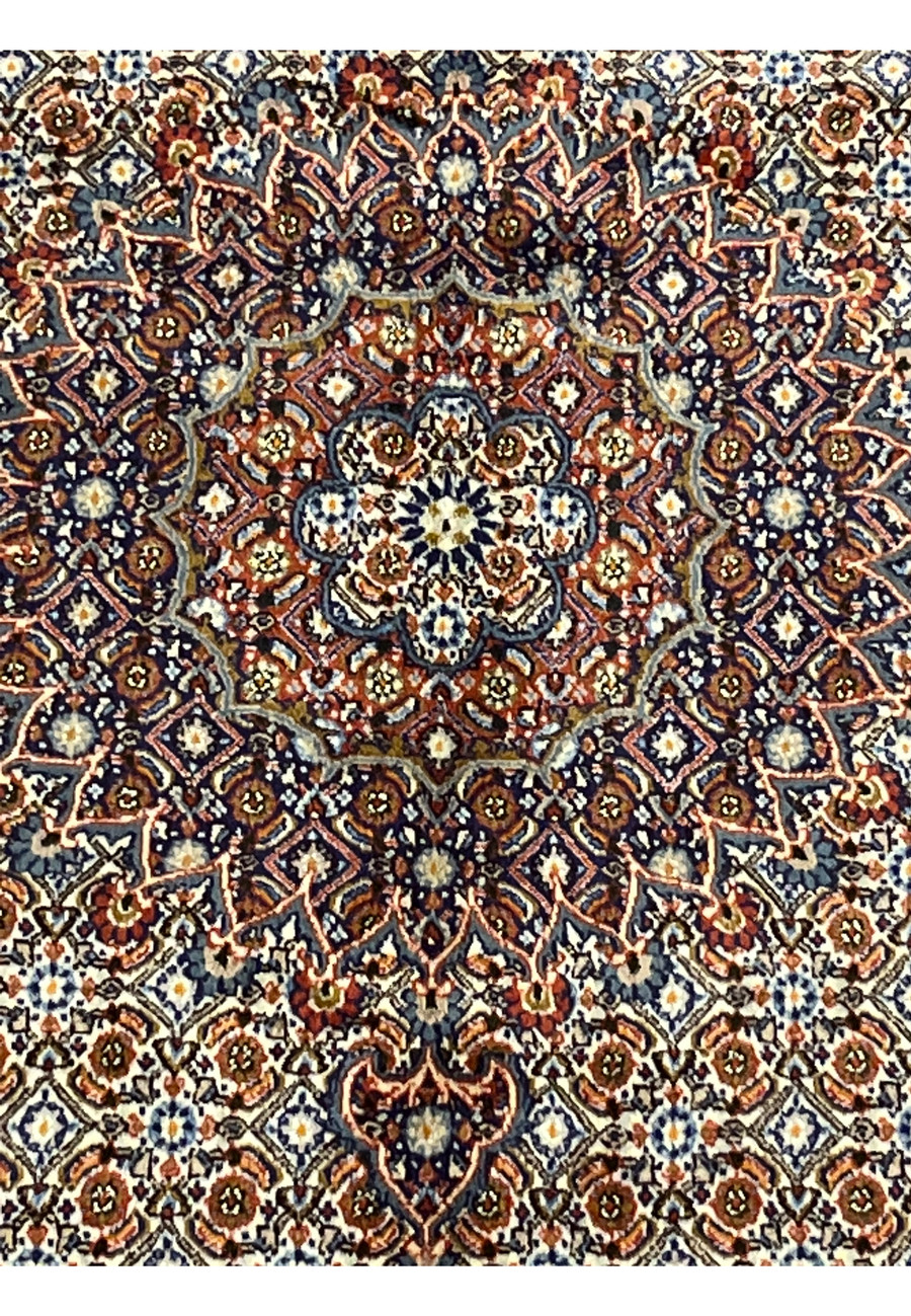 Macro view focusing on the medallion’s floral center, capturing the detailed knotting and interplay of navy, ivory, and terracotta hues typical of authentic Moud craftsmanship.