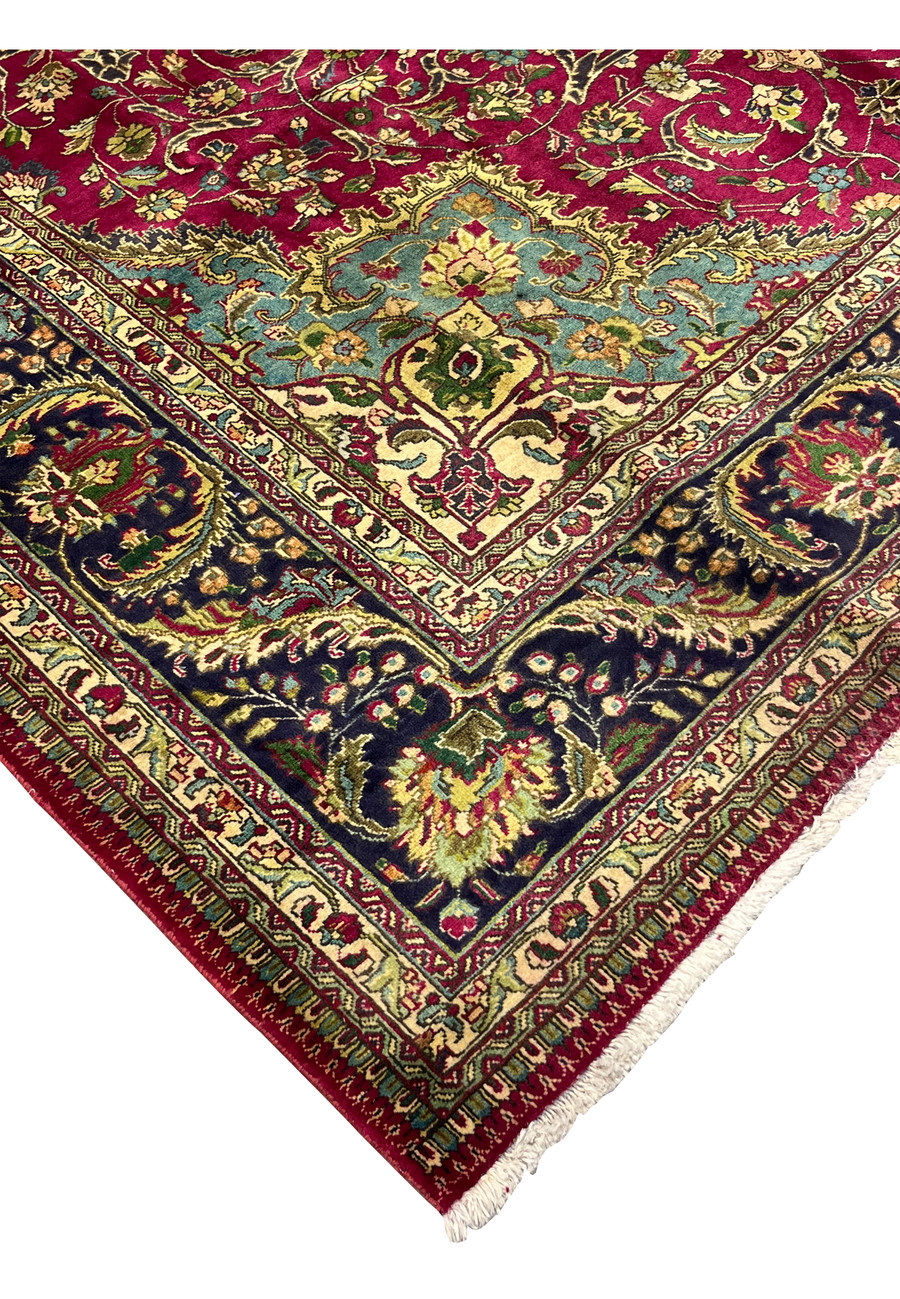 edge and fringe detail of Persian Tabriz rug with navy floral border and red outer band