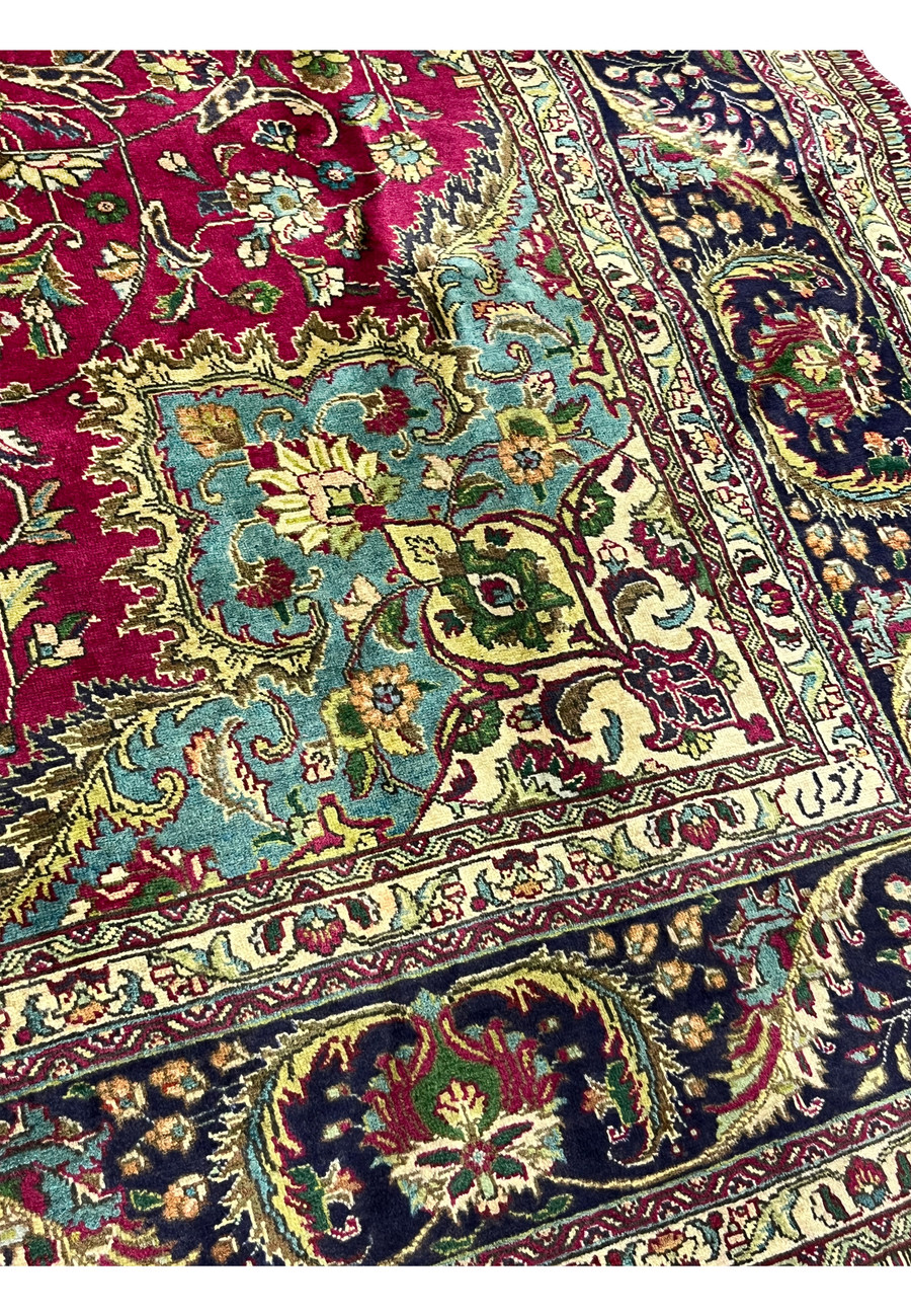 Detailed corner view of the 9'9 x 12'4 vintage Persian Tabriz rug showing turquoise corner spandrel, floral motifs, and navy border with fine wool pile.