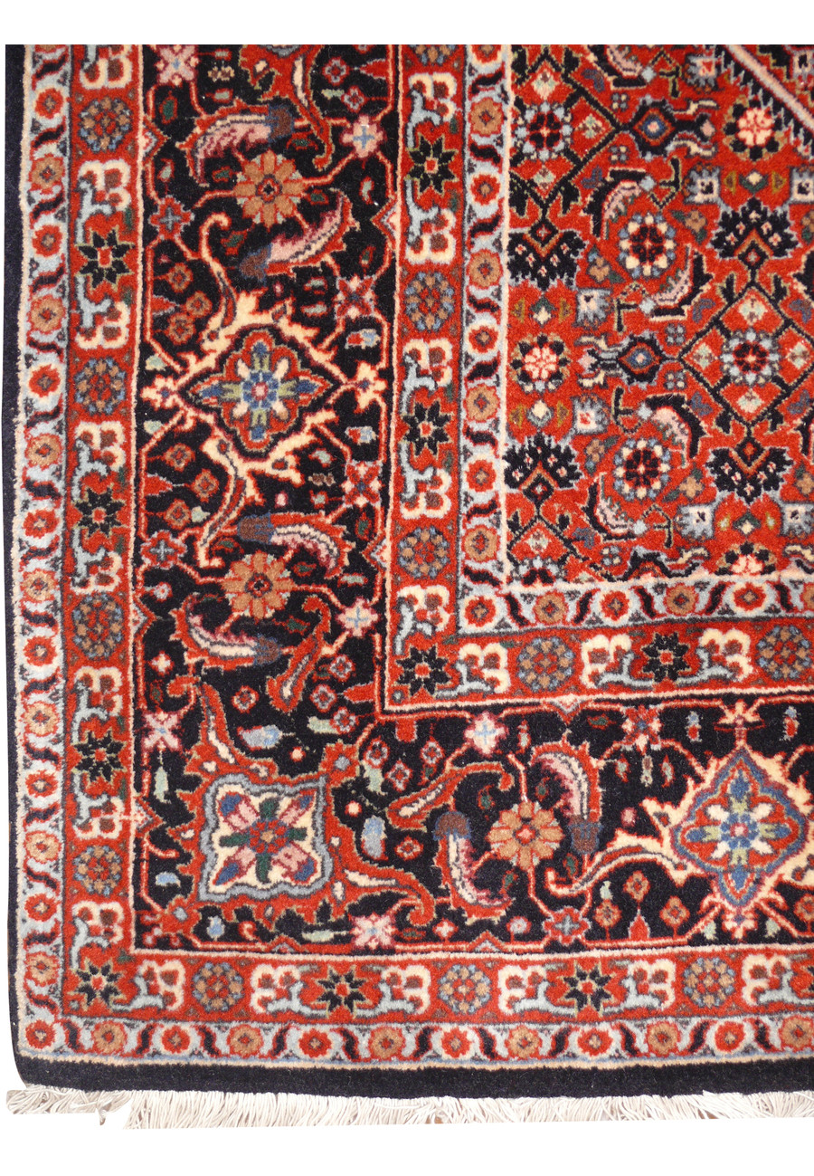 Detailed view of Bijar Persian iron rug border with repeating floral motifs on dark navy background
