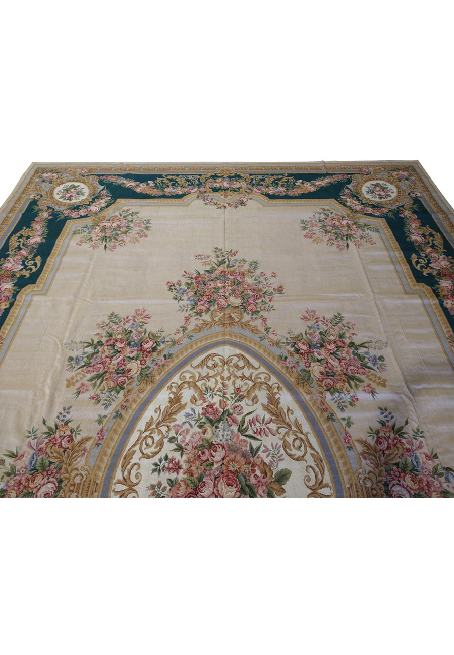 Upper section detail of French Aubusson rug highlighting emerald green border, pink rose garlands, muted gold scrollwork, and beige background