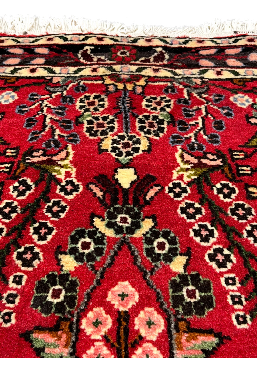 Upper section view of a Persian Darjazin rug showing floral vines, balanced medallion extensions, tight knot density, and harmonious tribal composition