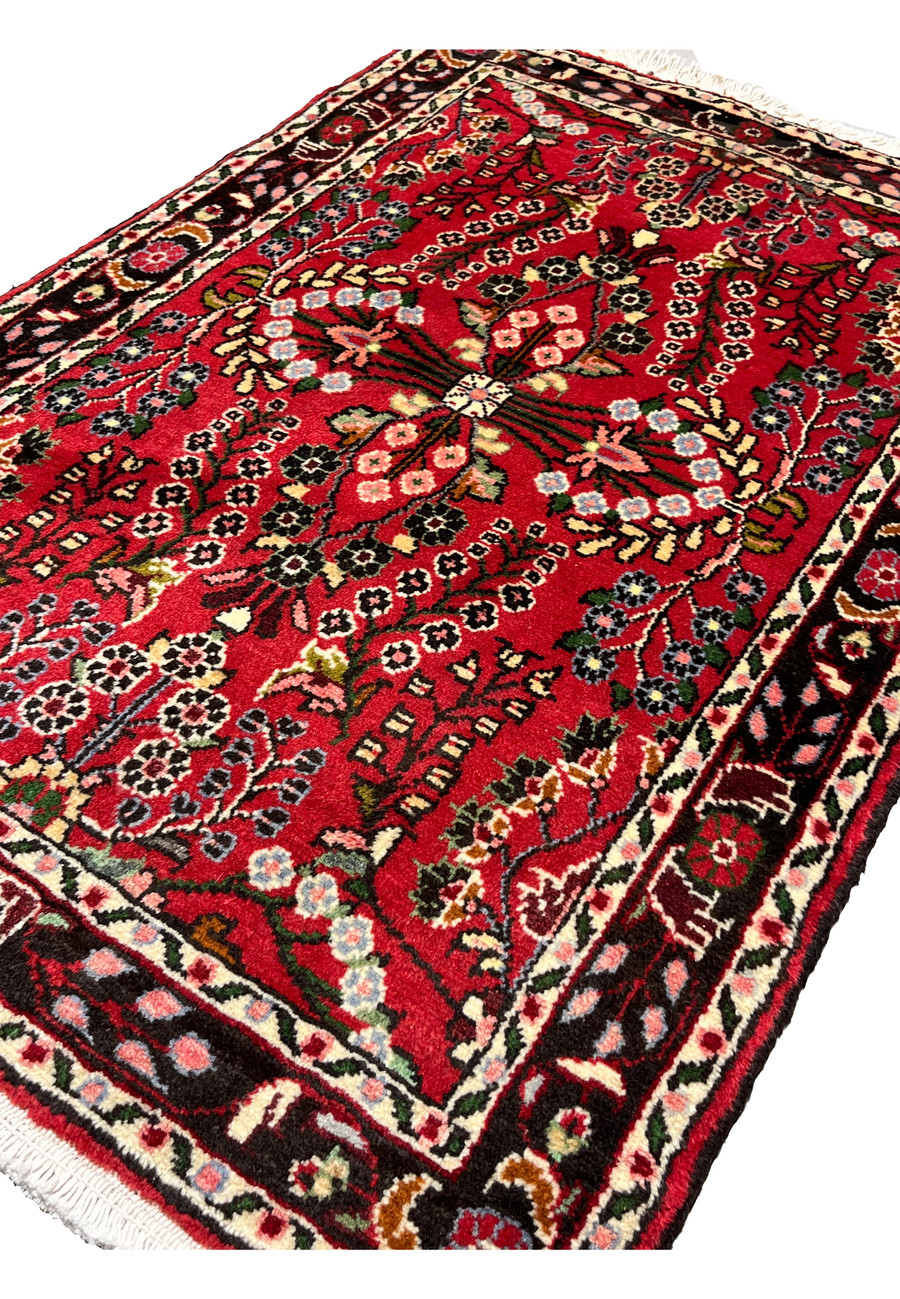 Angled perspective of a Persian Darjazin rug emphasizing pile height, dense knotting, vivid crimson tones, and dimensional floral motifs across the surface