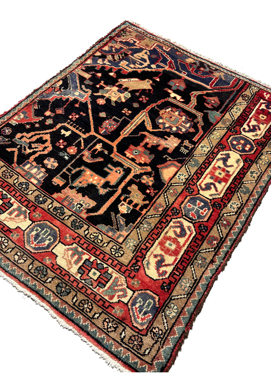 Angled perspective of antique Nahavand tribal rug highlighting depth, pile texture, pictorial motifs, and saturated indigo field