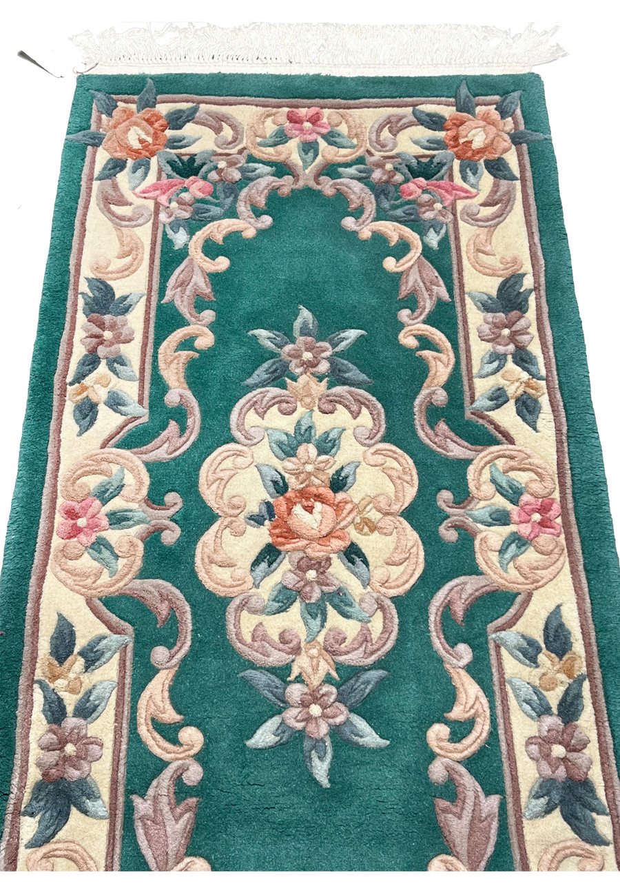 Detailed midfield image of emerald green Aubusson rug emphasizing sculpted floral vines and dimensional Art Deco decorative elements