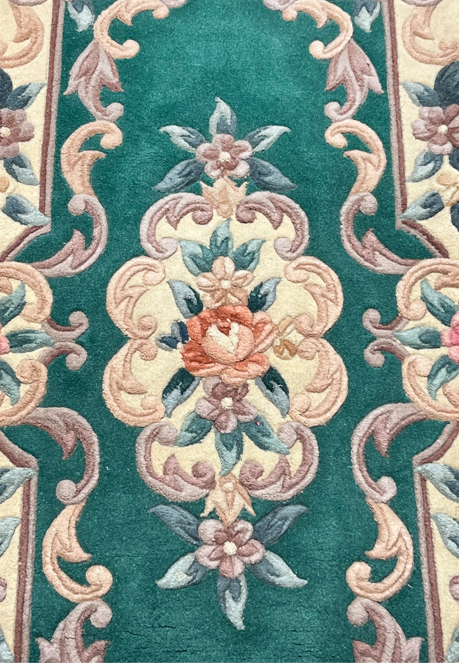 Close view of central floral motif on Aubusson Art Deco rug highlighting raised scrollwork texture and soft blush, sage, and ivory colors