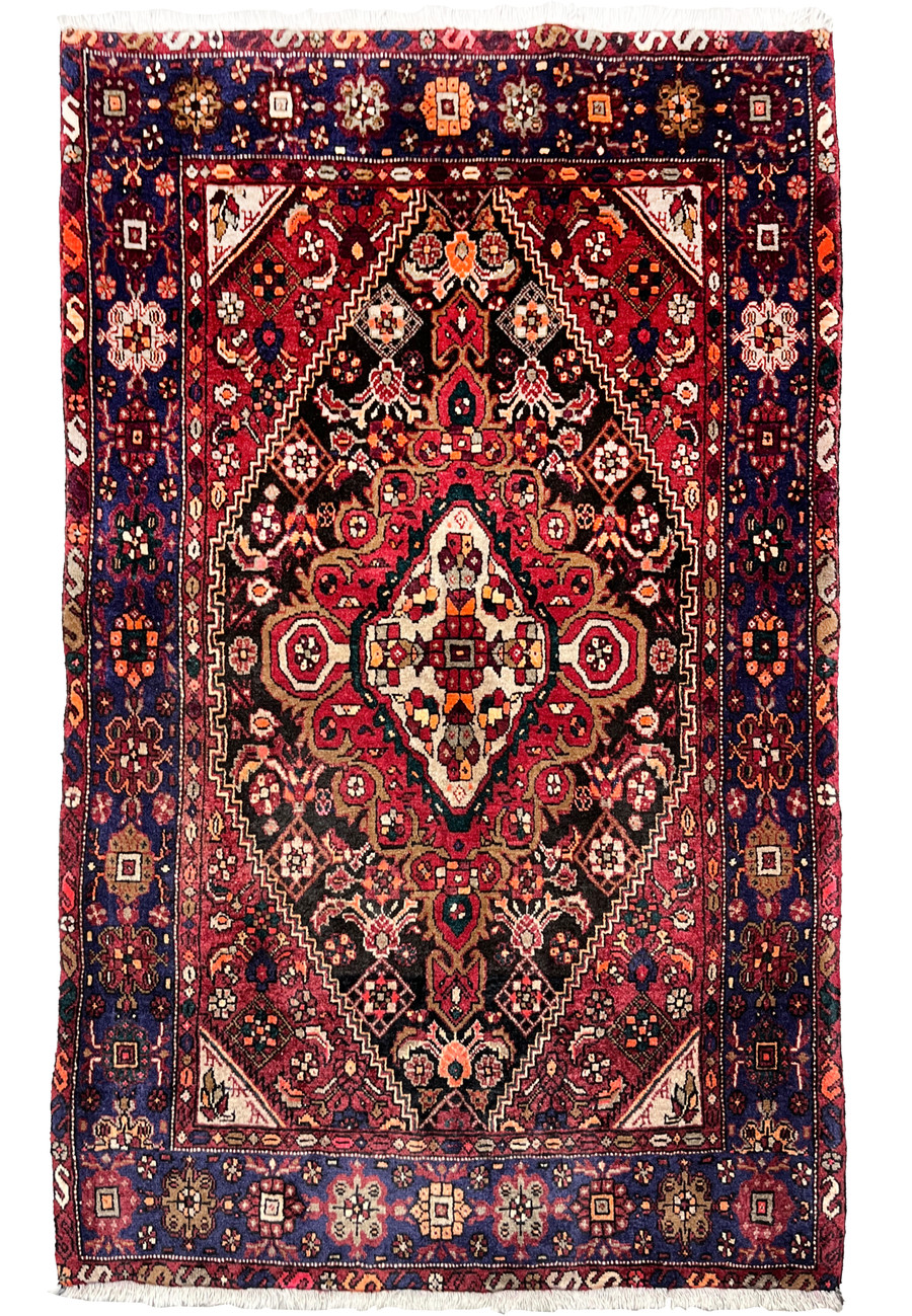 Full view of a 3'4 x 5'5 Persian Gholtogh rug with a deep red field, navy border, bold tribal medallion, and dense hand-knotted wool texture
