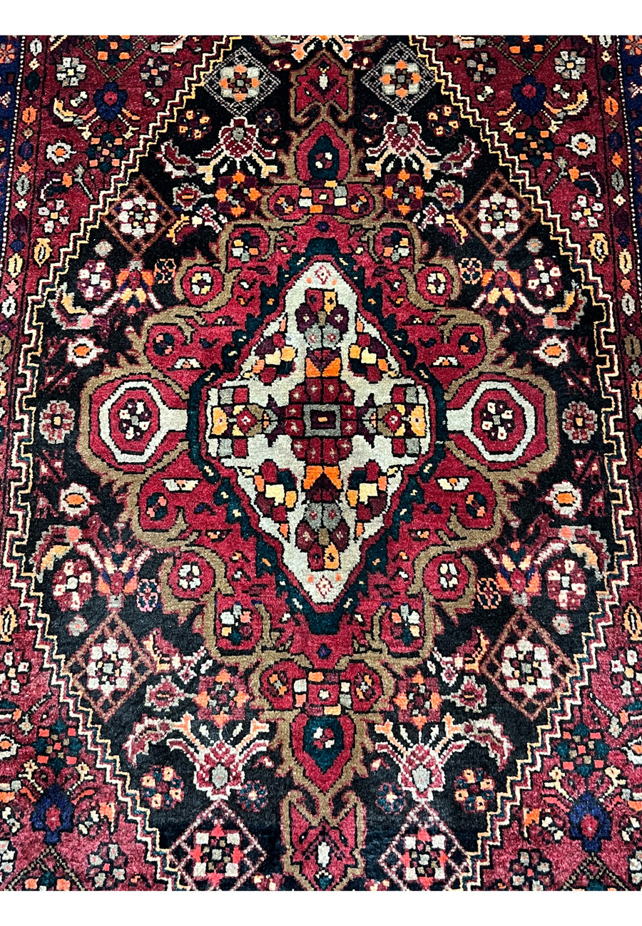 Central medallion detail of a Persian Gholtogh rug showing ivory highlights, geometric structure, burnt orange accents, and bold contrast