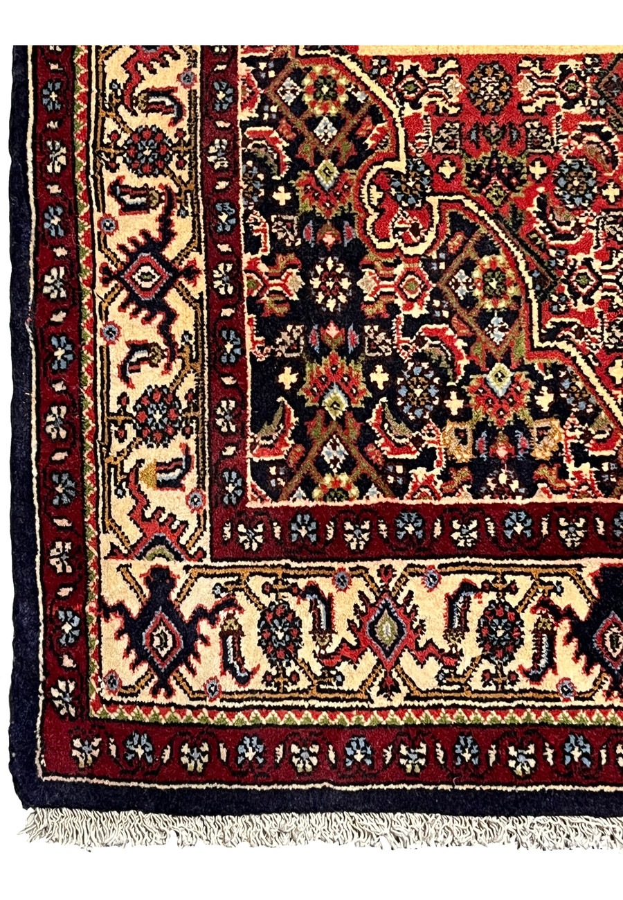 Border detail of a Persian Bijar rug showing repeating floral motifs, ivory ground, navy outlines, and precise hand-knotted craftsmanship
