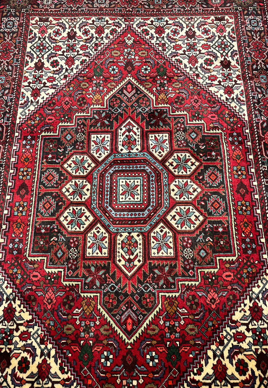 Midfield detail of a Persian Gholtogh rug featuring layered tribal motifs, ivory accents, angular geometry, and dense hand-knotted wool texture