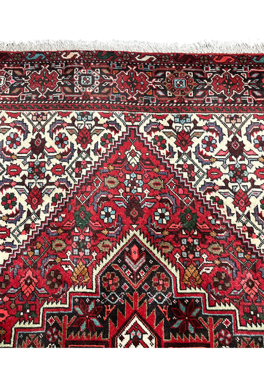 Upper border close-up of a Persian Gholtogh rug featuring geometric tribal motifs, ivory detailing, navy outlines, and crisp hand-knotted definition