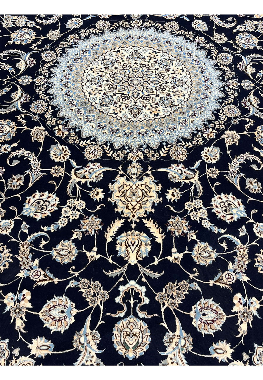 Lower field detail of Persian Nain Habibian silk rug showing scrolling floral motifs, silk sheen, and crisp contrast against navy background