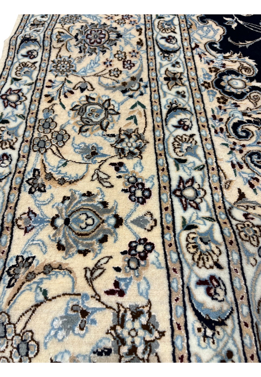 Closeup of ivory border on Persian Nain 6 LA Habibian rug featuring floral cartouches, silk highlights, and refined craftsmanship