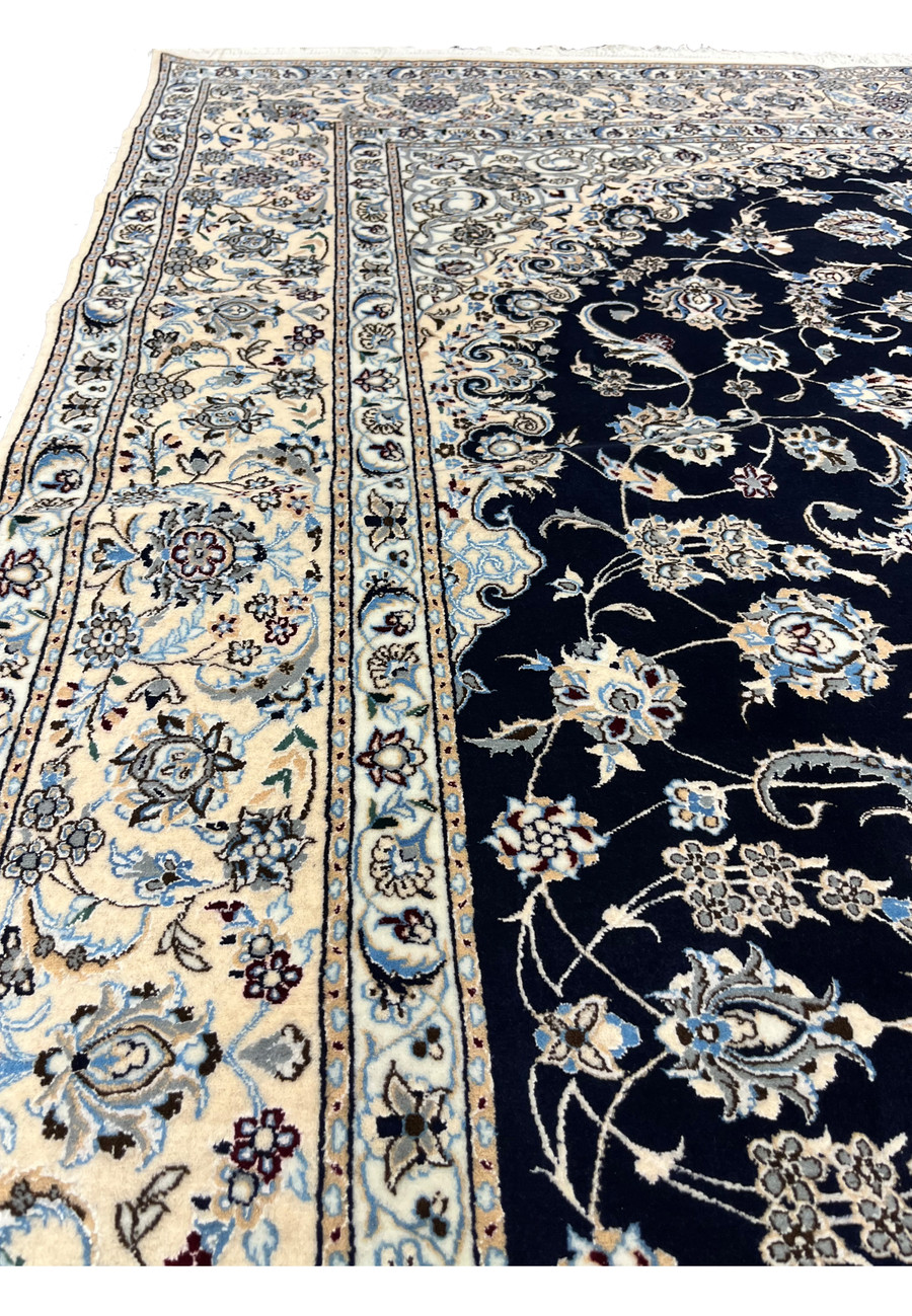 Angled side view of a 7x10 Persian Nain 6LA rug showing low, refined pile, crisp pattern definition, and elegant contrast between navy field and ivory border