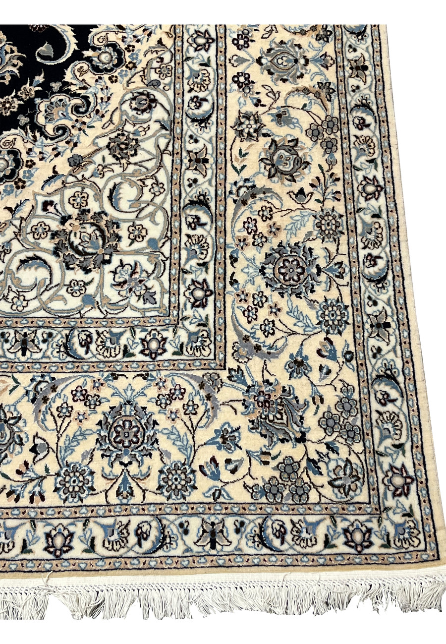 Border close-up of a Persian Nain Habibian rug showing intricate floral bands with ivory ground, pale blue blossoms, and fine navy outlining