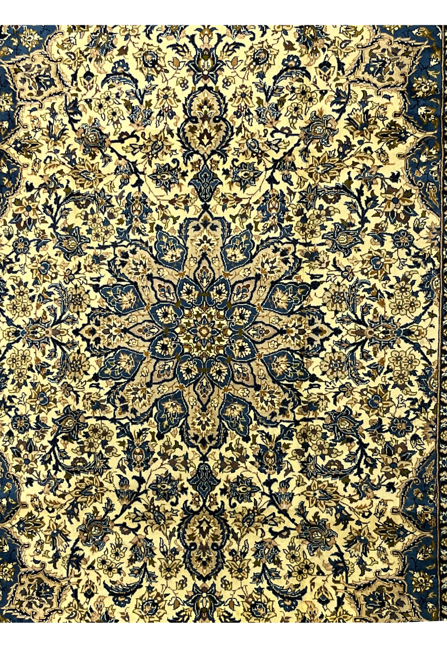 Central medallion detail of Persian Kashan rug in navy and gold tones layered floral rosettes on ivory ground