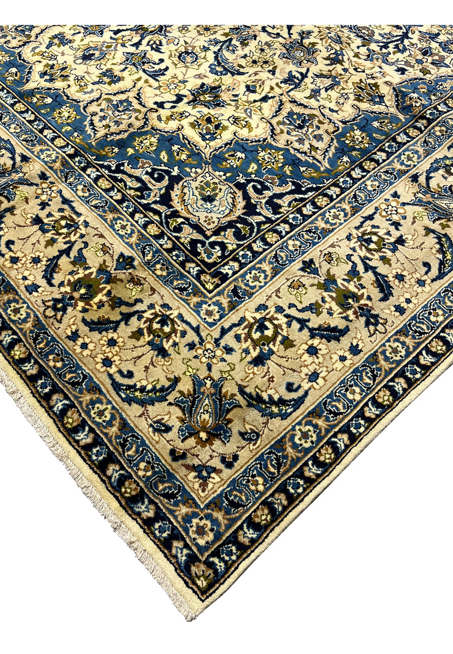 Edge detail of handmade Persian Kashan rug showing navy guard borders ivory field tight wool pile and finished fringe