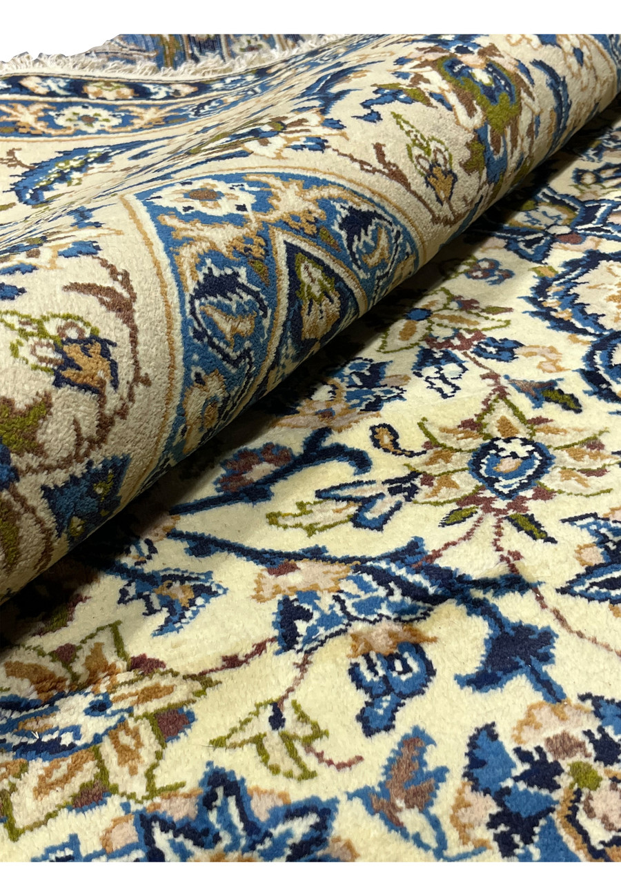Rolled view of oversized 10'2 x 14'3 Persian Kashan rug showing ivory floral field navy border thickness and plush wool pile texture