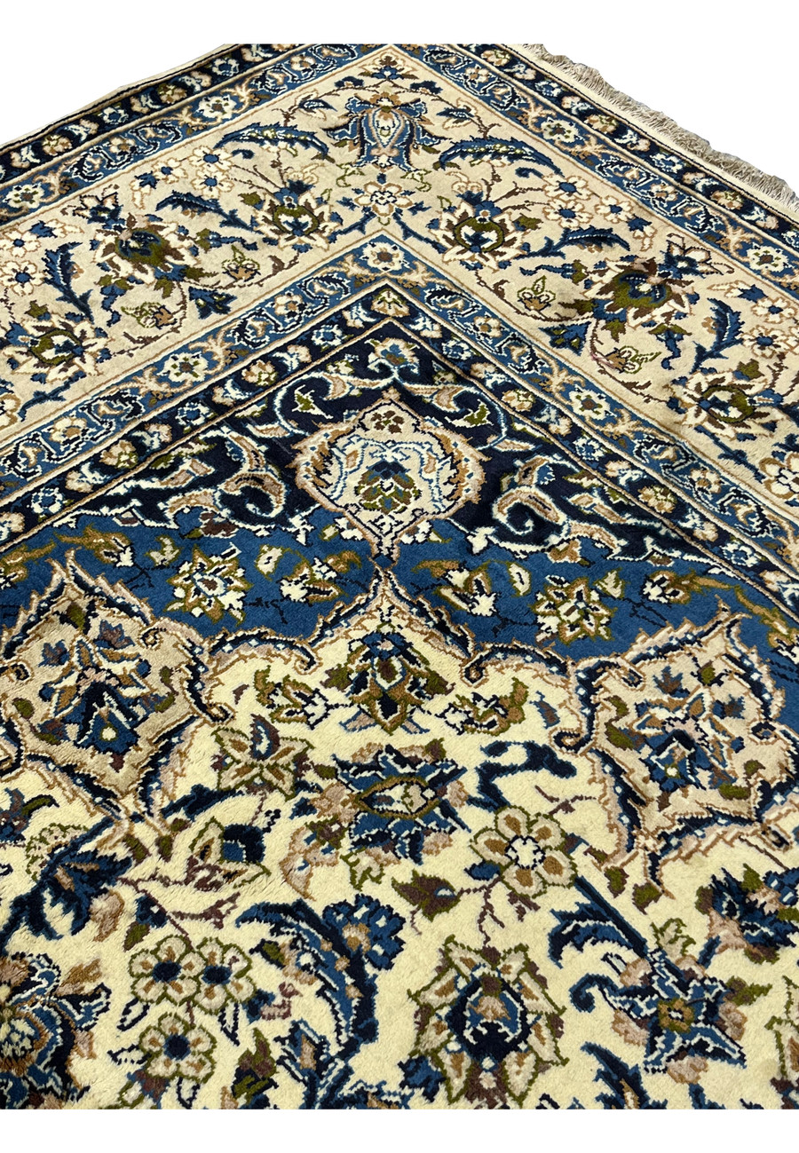 Upper edge detail of 10'2 x 14'3 Persian Kashan rug with ivory field navy floral border scrolling vines and hand knotted wool pile