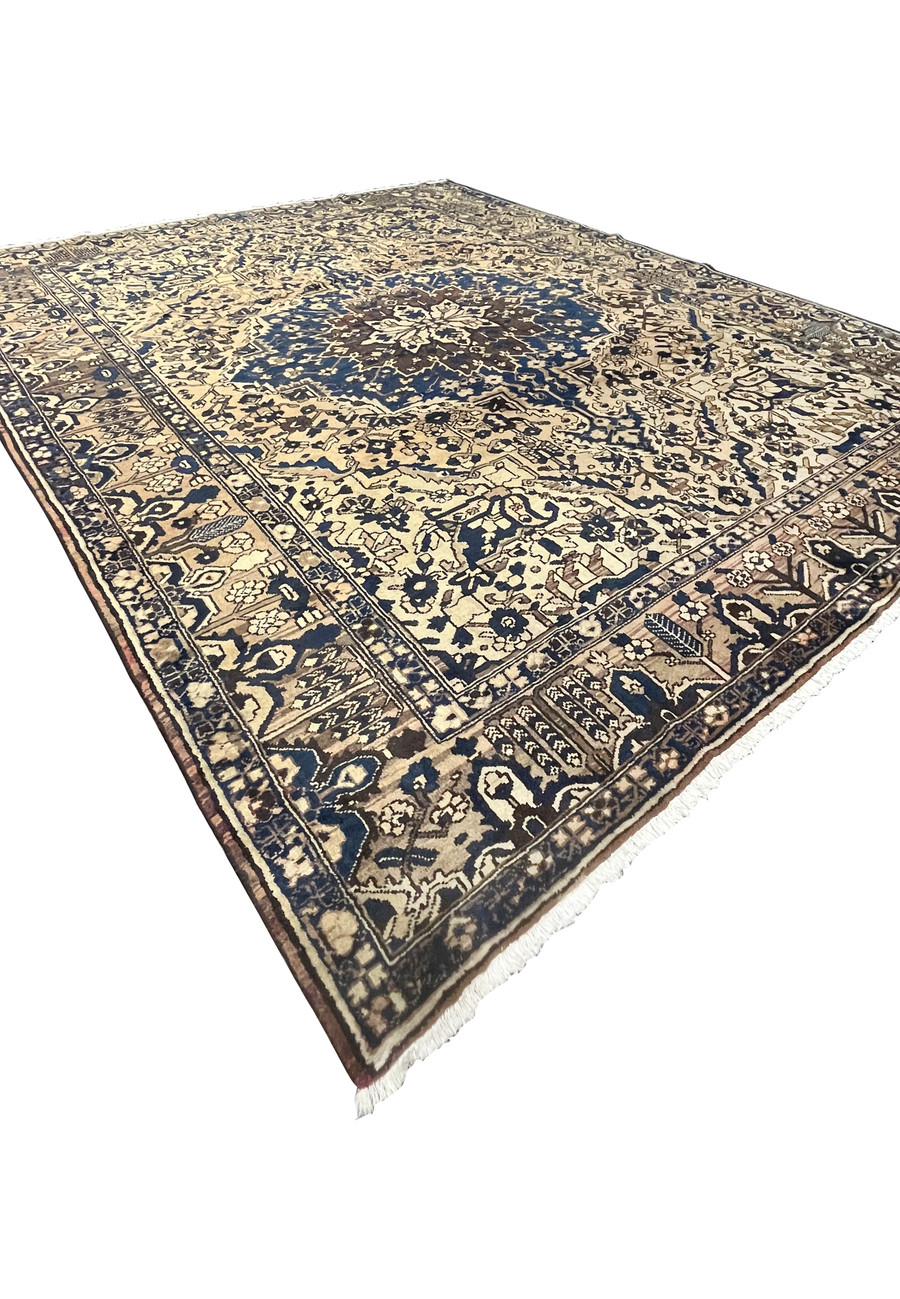 Angled perspective of oversized vintage Persian Heriz rug highlighting bold navy medallion and structured ivory field