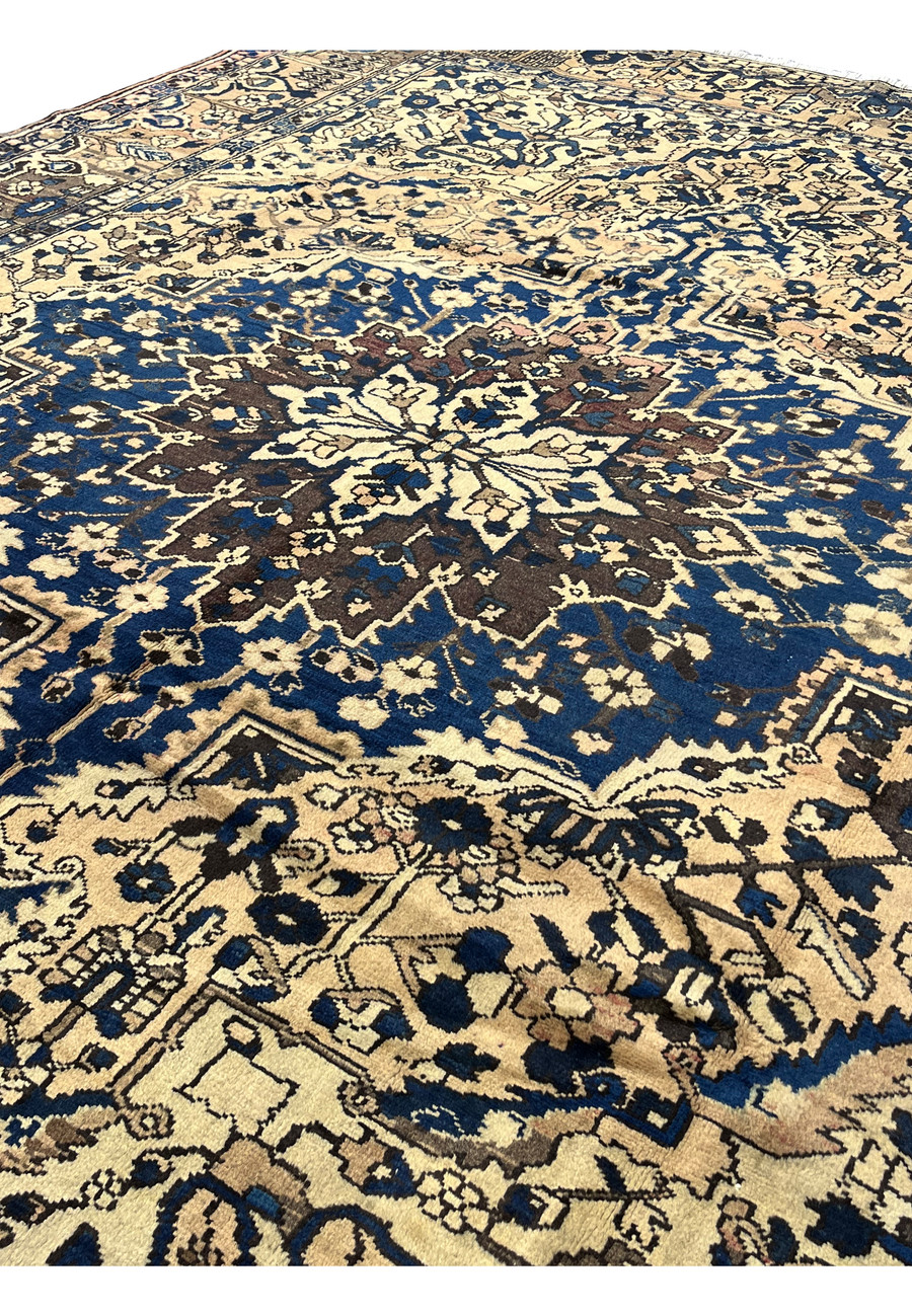 Center field detail of vintage Heriz rug showing ivory ground with navy geometric motifs and bold floral medallion