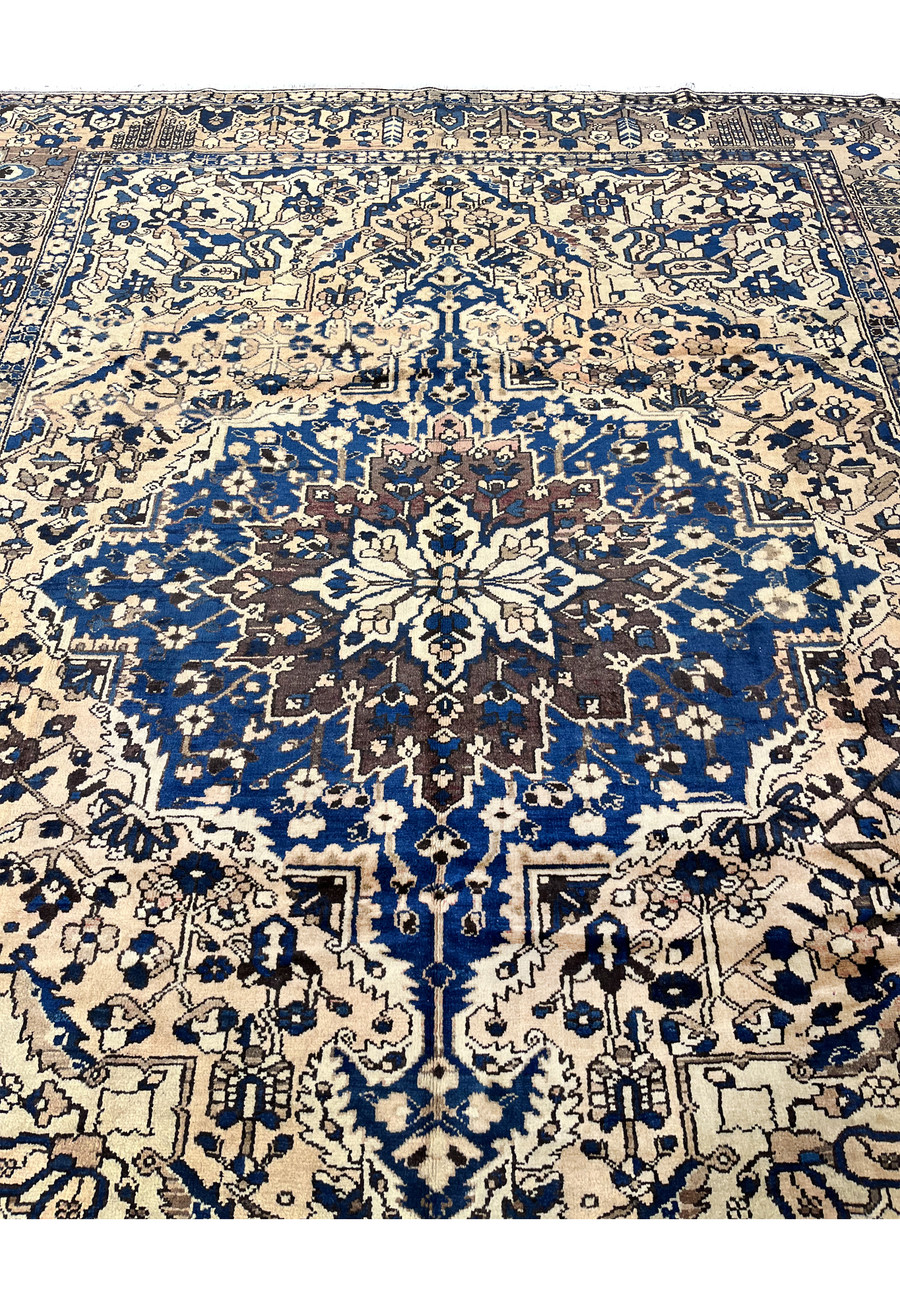 Detailed center medallion of vintage Heriz rug in muted navy blue and ivory wool with bold geometric floral design