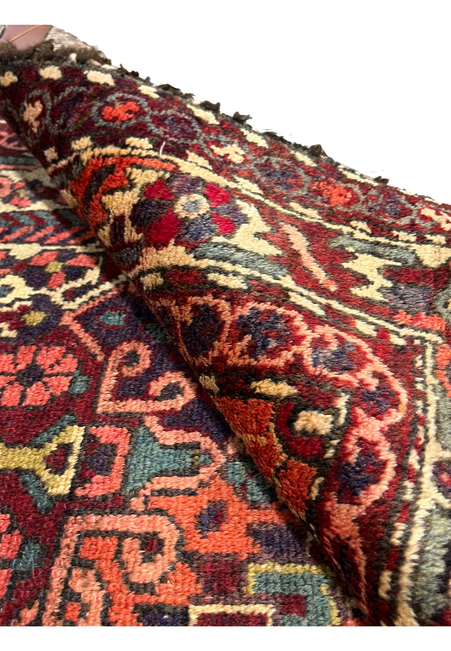 Antique 3'7x5 Persian Bakhtiari rug rolled showing wool pile depth and vintage character