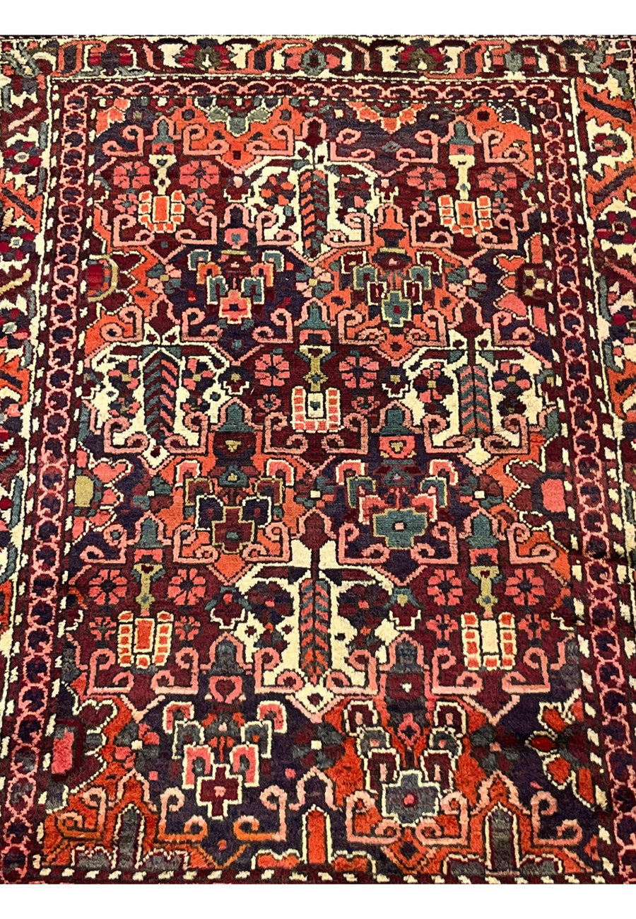 Midfield detail of antique 3'7"x5 Persian Bakhtiari rug with bold orange and navy floral motifs