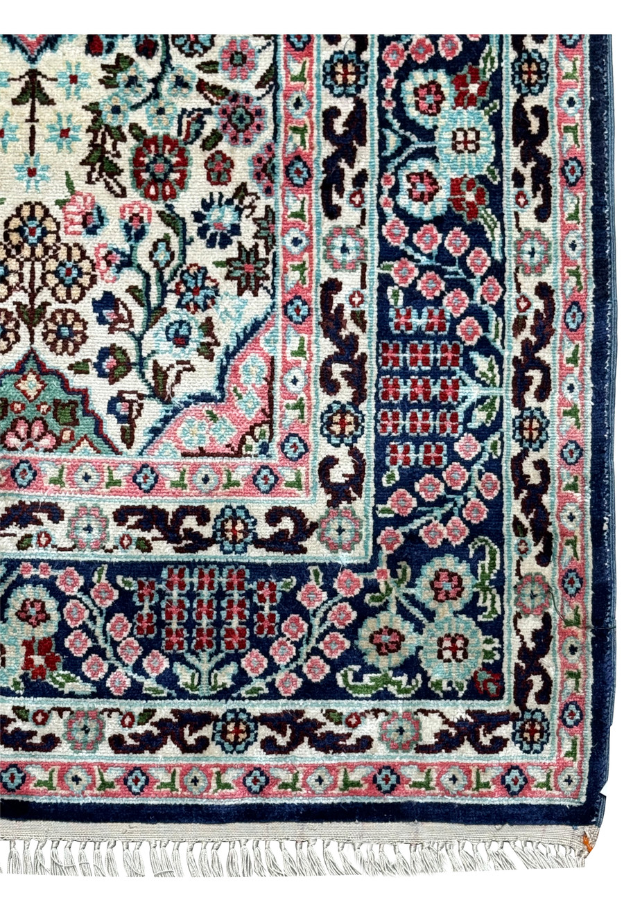 Close-up of the intricate border of a 3 x 5 Persian Qum Silk Rug, featuring floral and geometric patterns in navy and pink.