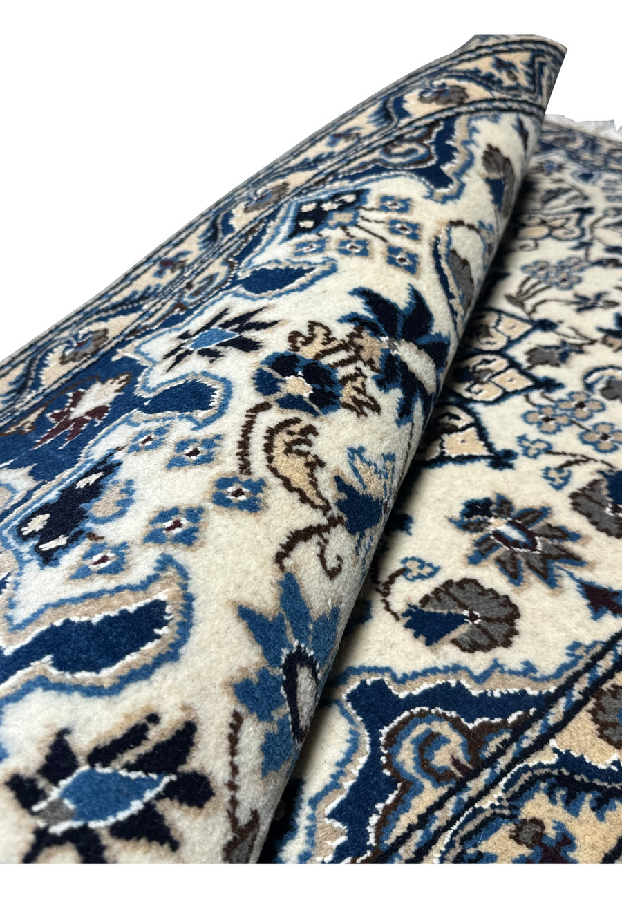 Rolled Persian Nain rug showing wool-silk texture and craftsmanship.