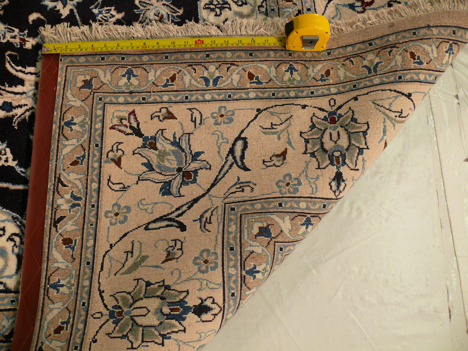 This picture displays the back of a Persian Nain wool and silk rug, measuring 8' x 11'. While most rugs are beautiful on their front side, this image showcases the impressive craftsmanship and attention to detail that goes into the making of this rug, even on its backside. The rug's exceptional quality is evident in the tight weave and the neatness of the knotting. This rug is a true work of art, from whichever angle you look at it.