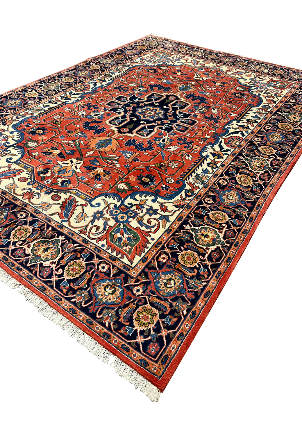 Angled perspective of a fine wool Persian Heriz rug highlighting pile texture, strong geometry, and rich red and navy colors