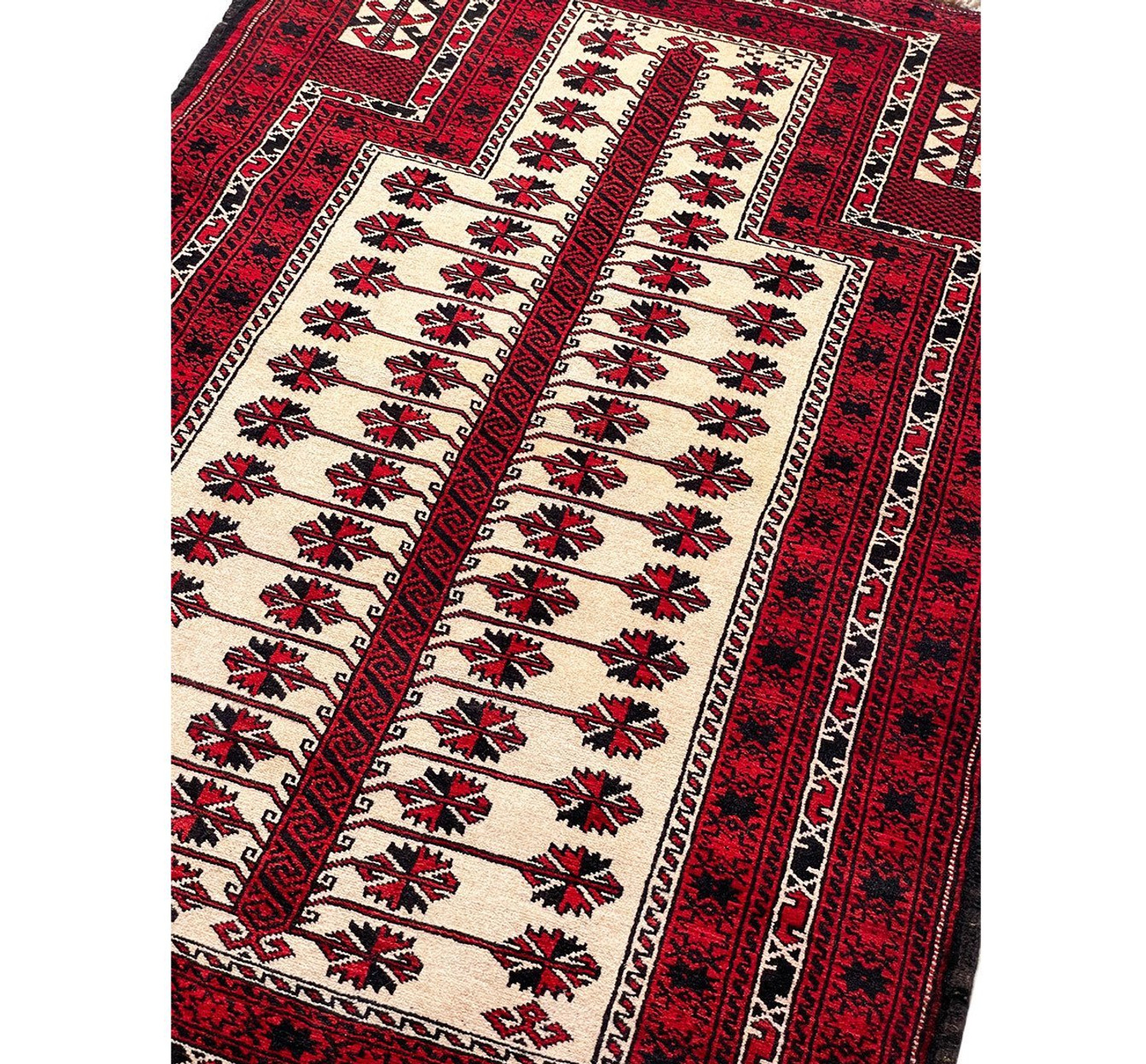 Detailed shot of the middle field of the Persian Baluch rug featuring unique diamond-shaped motifs and bursts of color