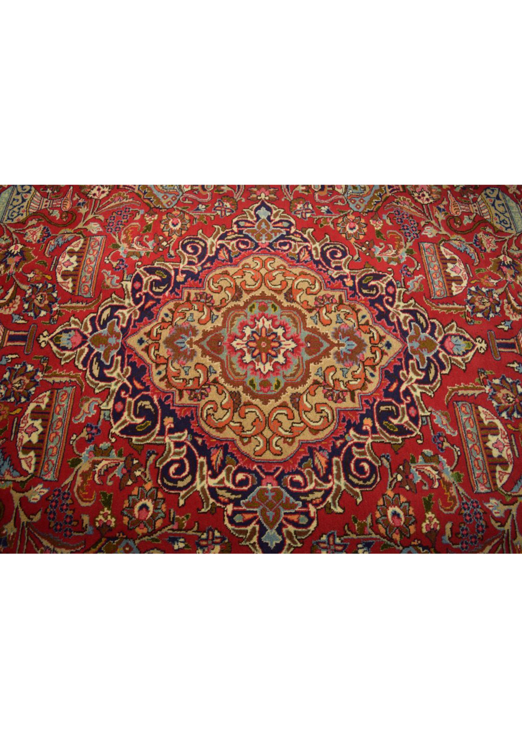 A detailed view of the central medallion of the Persian Kashmar rug, featuring intricate designs and a rich mix of red, gold, and blue hues