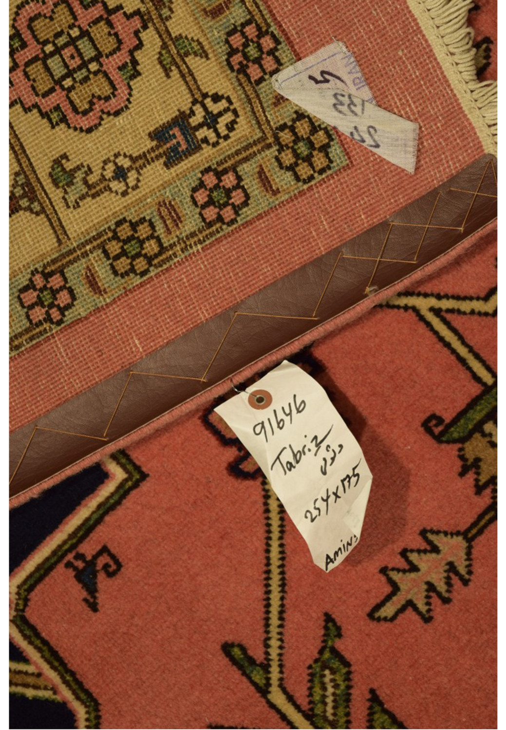 Image of a Persian Tabriz rug's label and corner, providing authenticity details with visible craftsmanship and fiber quality.