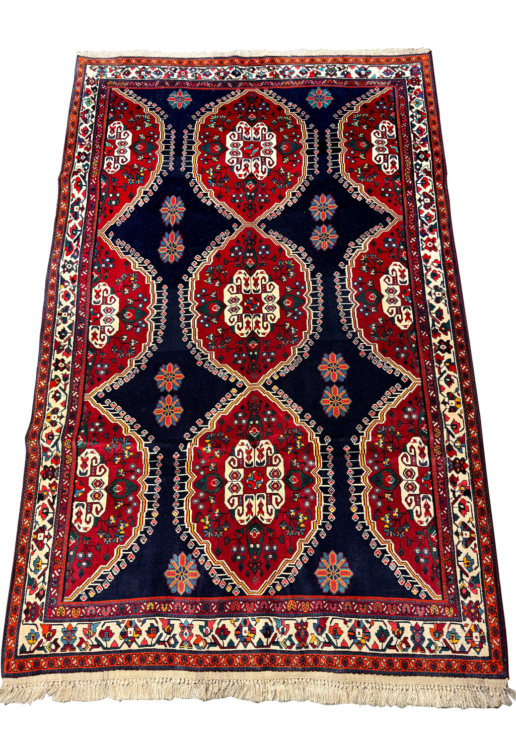 Edge of a Persian Qashqai rug highlighting the detailed border patterns with geometric and floral designs in a multicolor scheme on a white fringe background