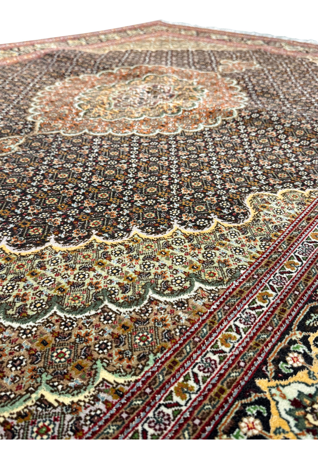 A partial view of the 5x7 Persian Tabriz Mahi 50 Raj Rug focusing on the ornate edge patterns and the textural quality of the weave